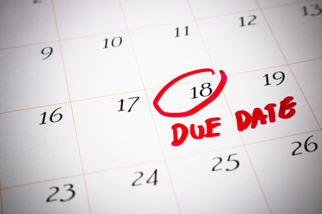 A close-up view of a monthly wall calendar page focusing on the 18th day of the month, which is circled in bright red marker with the words "DUE DATE" written boldly underneath it in red ink.