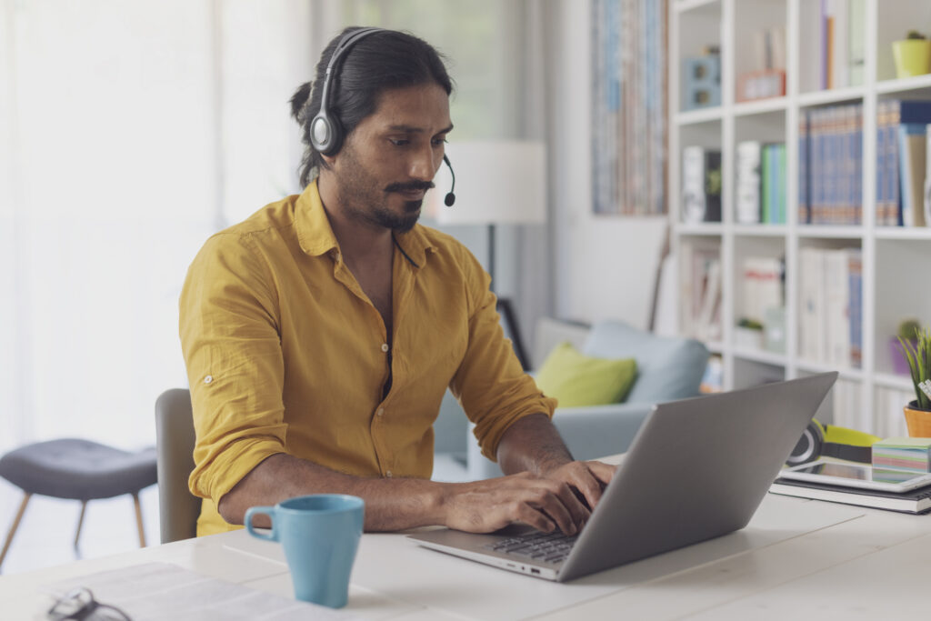 A dedicated medical billing specialist wearing a headset focuses on processing claims on a laptop in a brightly lit, professional corporate workspace.