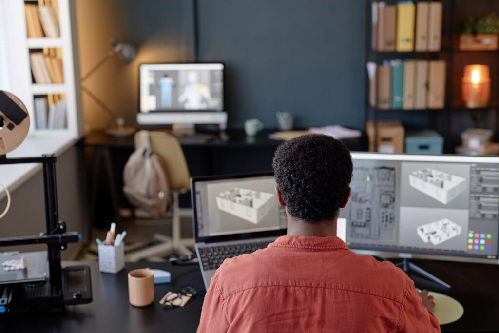 An architectural designer working on a detailed 3D building model using BIM software on dual computer monitors