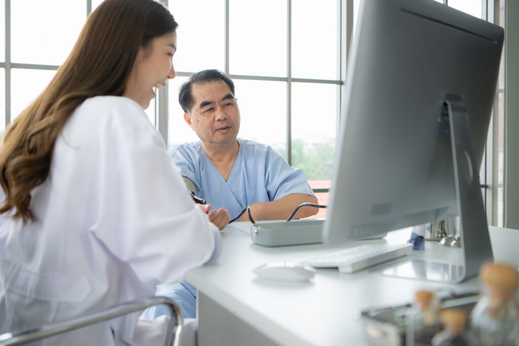 A medical team using a calculator and laptop to analyze billing workflows and revenue metrics in a clinic office