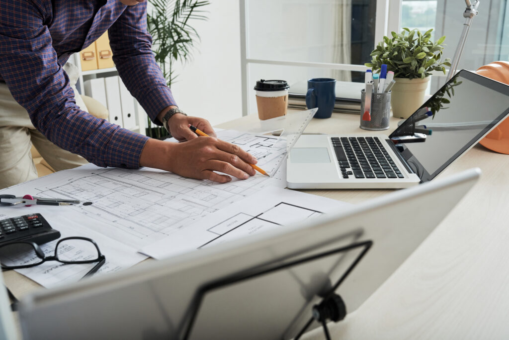 Architect reviewing blueprints and project scope document inclusions to prevent unbudgeted redesigns in an A&E firm