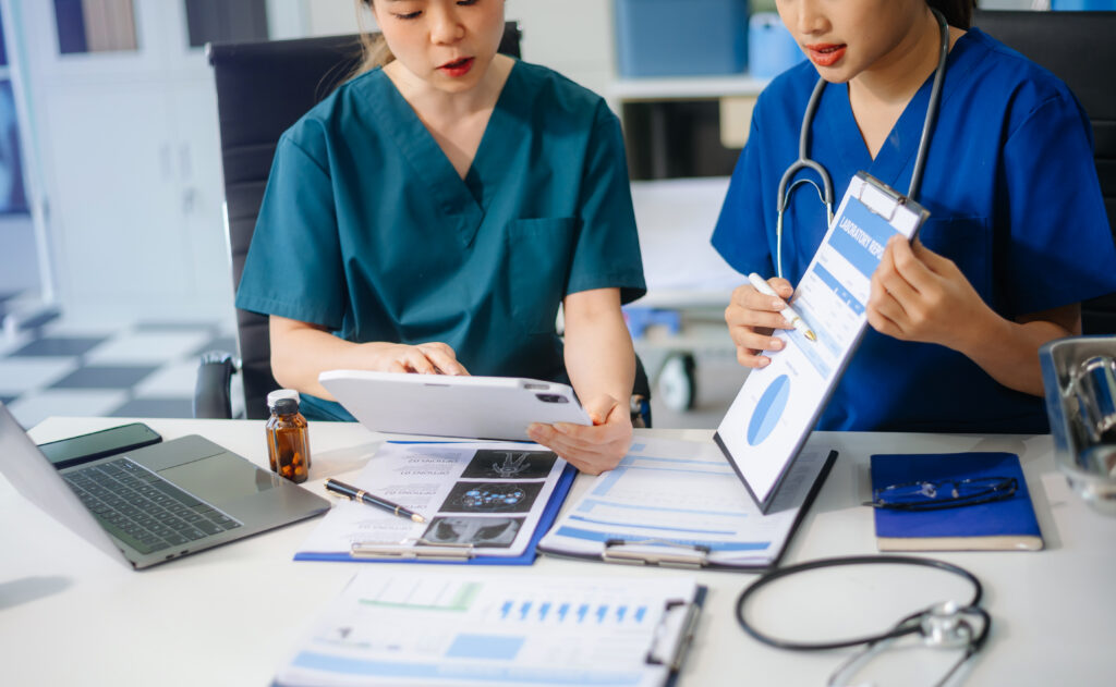 Two healthcare staff reviewing lab reports and claims data on a tablet