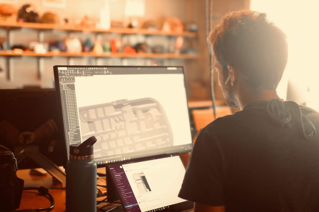 Production professional working on a detailed 3D CAD model at a dual-screen design workstation